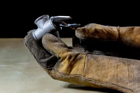 Hand in glove with tool for work in workshop. Hand protected by working coat. Stock Photos