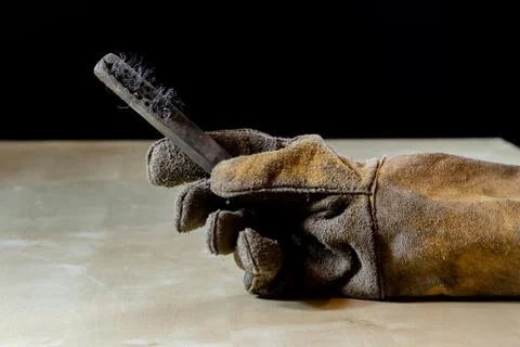 Hand in glove with tool for work in workshop. Hand protected by working coat. Stock Photos