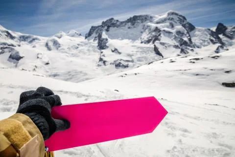 Hand in glove touching empty directional sign post with winter snow mountain 库存照片