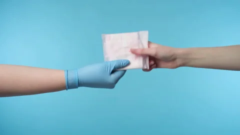 Hand in gloves give sanitary pad to woman Stock Footage