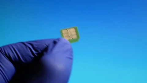 Hand in gloves holding green micro SIM card on blue background. Stock Footage 130814080