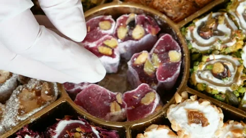 Hand in gloves put tasty different sorts eastern sweets in box Video stock 123145390