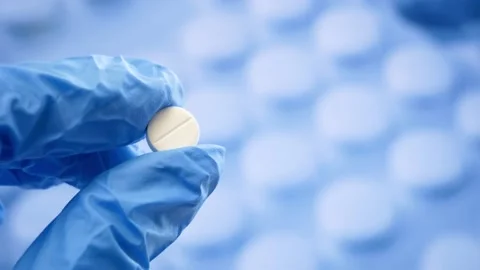 Hand in gloves takes pill on large group of assorted capsules, pills, tablets Stock Footage 165322397