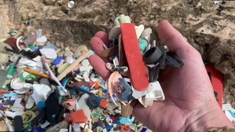 Hand going through microplastics that washed up on shore and showing Stock Footage 146633806