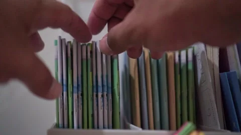 Hand grab and take a book from bookshelf, organized colorful books, reading and Stock Footage 344011344