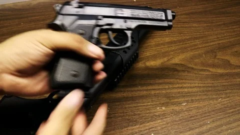 Hand Grabbing and Loading Pistol on Wood Table Stock Footage 79601129
