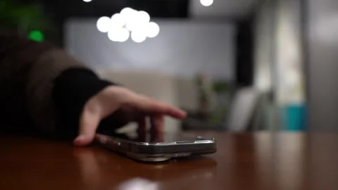 A hand grabbing and picking up a mobile phone on restaurant table Stock Footage 330279091