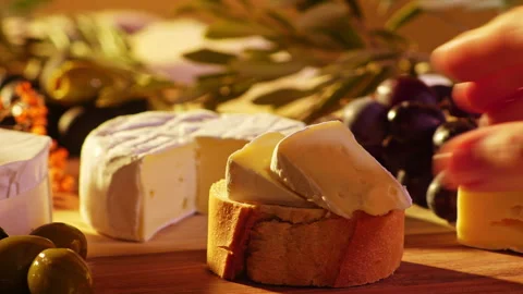 Hand Grabbing Bread Slice with Camembert Cheese on Rustic Charcuterie Board Stock Footage 334266869