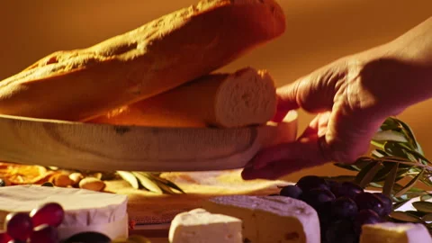 Hand Grabbing Bread Slice from Rustic Charcuterie Board with Grapes and Stock Footage 334267534