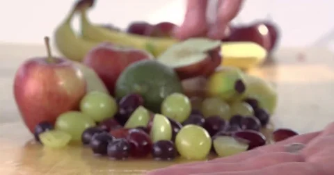 Hand grabbing fruit off table on white background Stock Footage 69287857