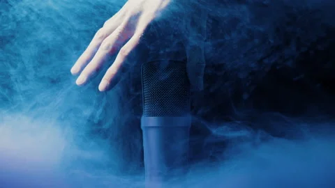 Hand grabbing a microphone in blue liquid on a black background 스톡 동영상 130704703