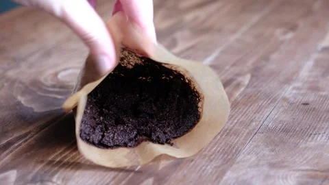 Hand grabbing use cone coffee filter on a wooden table, used ground coffee .. Stock Footage 297635661