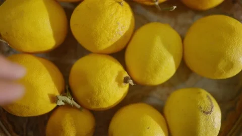 Hand grabs lemon out of fruit bowl in the early morning. Stock Footage 142033665