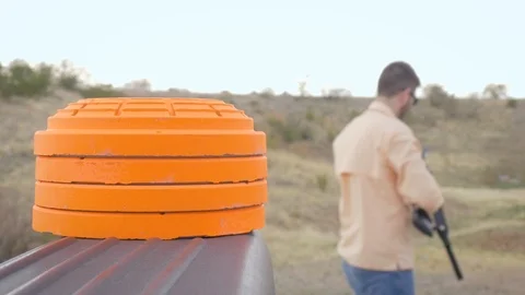 Hand Grabs an Orange Clay Pigeon with a Young Man Shooting Target Practice in 4k Stock Footage 88559361
