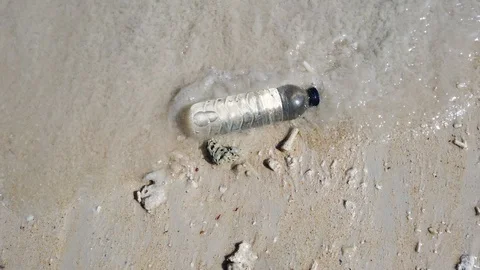 A hand grabs a plastic bottle dumped on the beach Stock Footage 111181774