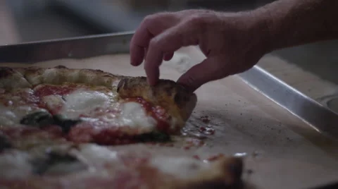 A hand grabs a slice of pizza with a shallow depth of field - 4k Stock Footage 64806406