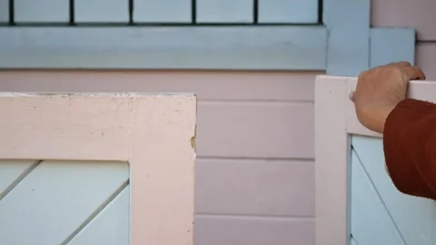 A hand gracefully rests on a beautifully designed pink and blue gate at the Stock Footage 289162738