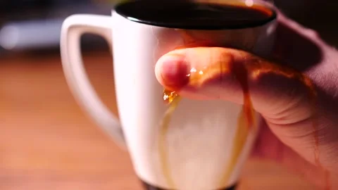 Hand grasping a mug of overflowing hot coffee Stock Footage 153667692