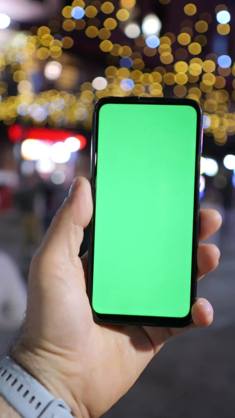 A Hand Grasping a Smartphone Featuring a Green Screen Set Against a Festive Stock Footage 296730526