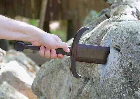 Hand grasping the sword in the stone representing the legend of King Arthur Fotos Stock