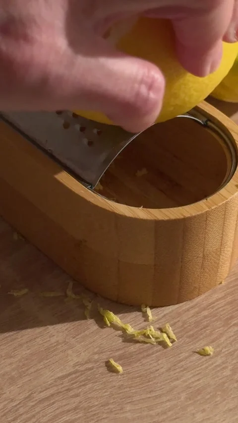 Hand grating fresh lemon zest on a bamboo grater Stock Footage 336809399