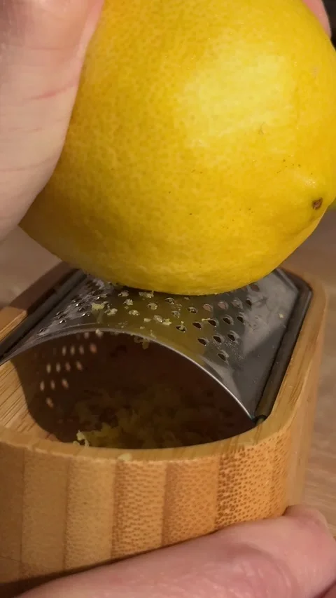 Hand grating fresh lemon zest on a bamboo grater Stock Footage 336995790