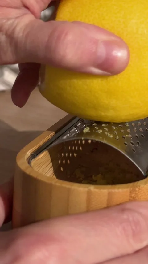 Hand grating fresh lemon zest on a bamboo grater Stock Footage 337558850