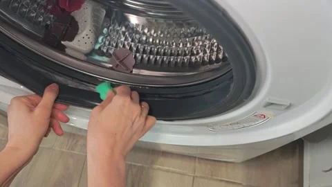 Hand with green sponge cleaning rubber seal of front‑loading washing machine Stock Footage 346457631