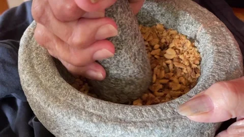 Hand Grinding Roasted Peanuts In Stone Mortar And Pestle Stock Footage 332837373