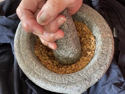 Hand Grinding Roasted Peanuts With Stone Mortar And Pestle Foto stock