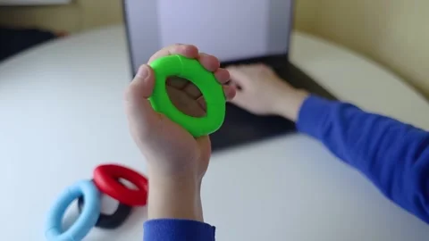 Hand gripper. Man squeezes rubber expander while working on his laptop. Concept  Stock Footage 265652728