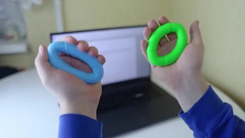 Hand gripper. Man squeezes rubber expander while working on his laptop. Concept  Stock Footage 265652988