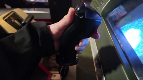 Hand gripping and pressing buttons on vintage arcade game joystick in dim roo Stock Footage 343681956