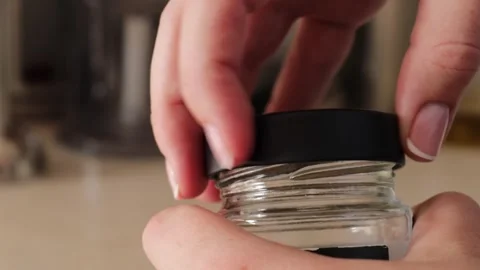 Hand gripping and rotating a silver metal lid on a transparent glass jar, p.. Stock Footage 320738235