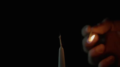 Hand gripping match lighting candle on dark background closeup. Bright flame Stock Footage 332506404