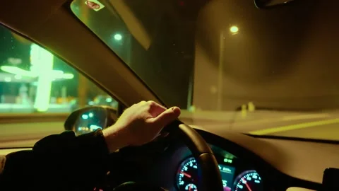 Hand gripping steering wheel while unrecognizable man driving past gas station Stock Footage 324960474