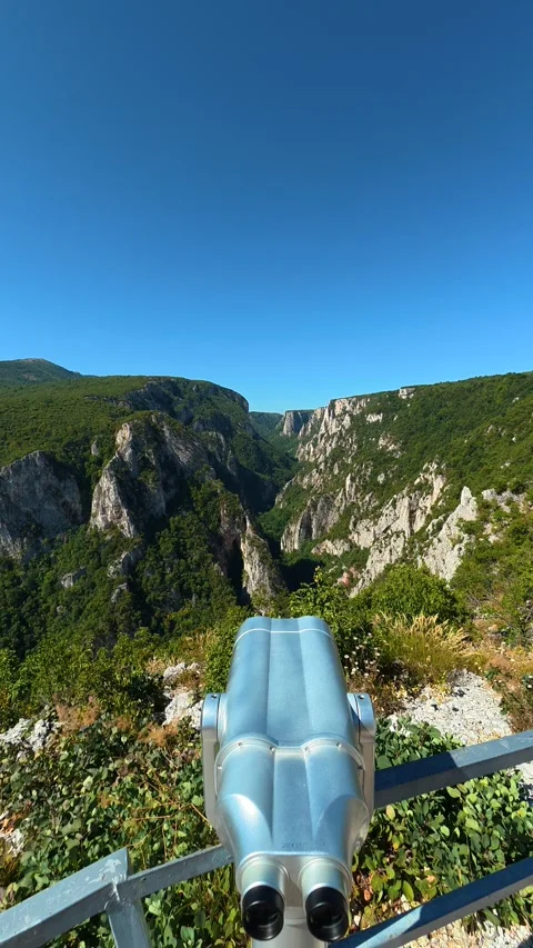 Hand grips binoculars, gazing at distant cliffs. Lazar's Canyon, Serbia Vertical Stock Footage 345338297