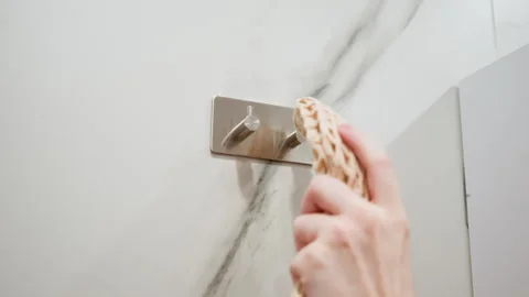 Hand guiding woven macrame bag onto brushed metal wall hook in pale interior Stock Footage 343543183
