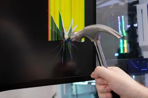 Hand with a hammer violently smashes a computer monitor, creating a shatter.. 스톡 사진