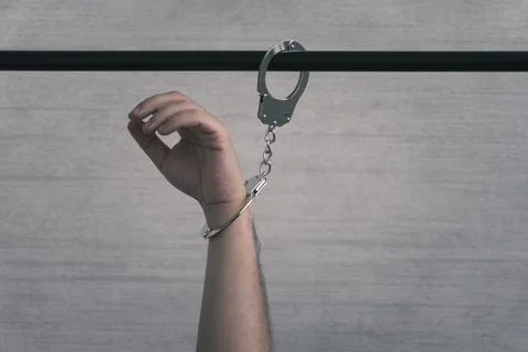 Hand in handcuffs, fastened to pipe close-up Stock Photos
