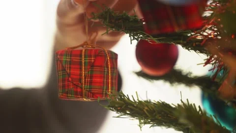 Hand hangs Christmas present gift box ornament or decoration from christmas tree Stock Footage 287017349