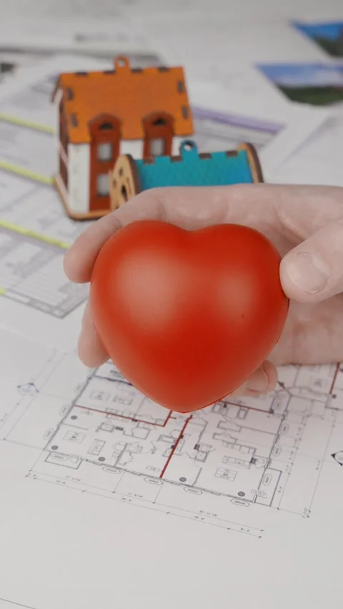 A hand with a heart in the background of blueprints with two house models Video stock 305636416