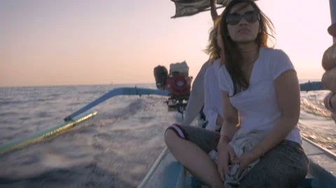 Hand held 4k footage of three tourists on a small motor boat during sunrise Stock Footage 57102433