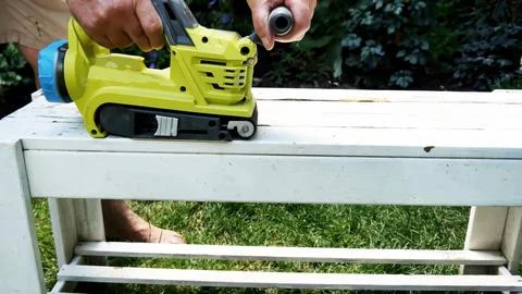 Hand-held battery powered belt sander to level the surface on garden furnitur Stock Photos
