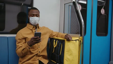 Hand-held camera. A deliveryman in a protective mask rides in a subway car Stock Footage 239323565