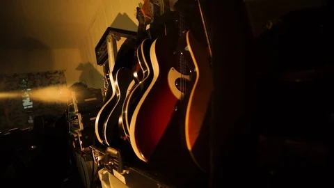 A hand held camera holds on a row of guitars in a garage band practice Stock Footage 102828053