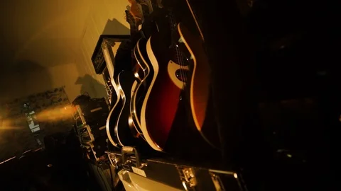 A hand held camera holds on a row of guitars in a garage band practice Stock Footage 102828355