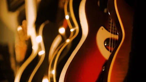 A hand held camera pans across a row of guitars in a garage band practice Stock Footage 102828064