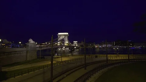 Hand-held camera shot of Chain Bridge by night with cyclists Stock Footage 79760584