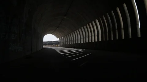 Hand held camera walking through and getting out a brutalist concrete tunnel. 스톡 동영상 95555879
